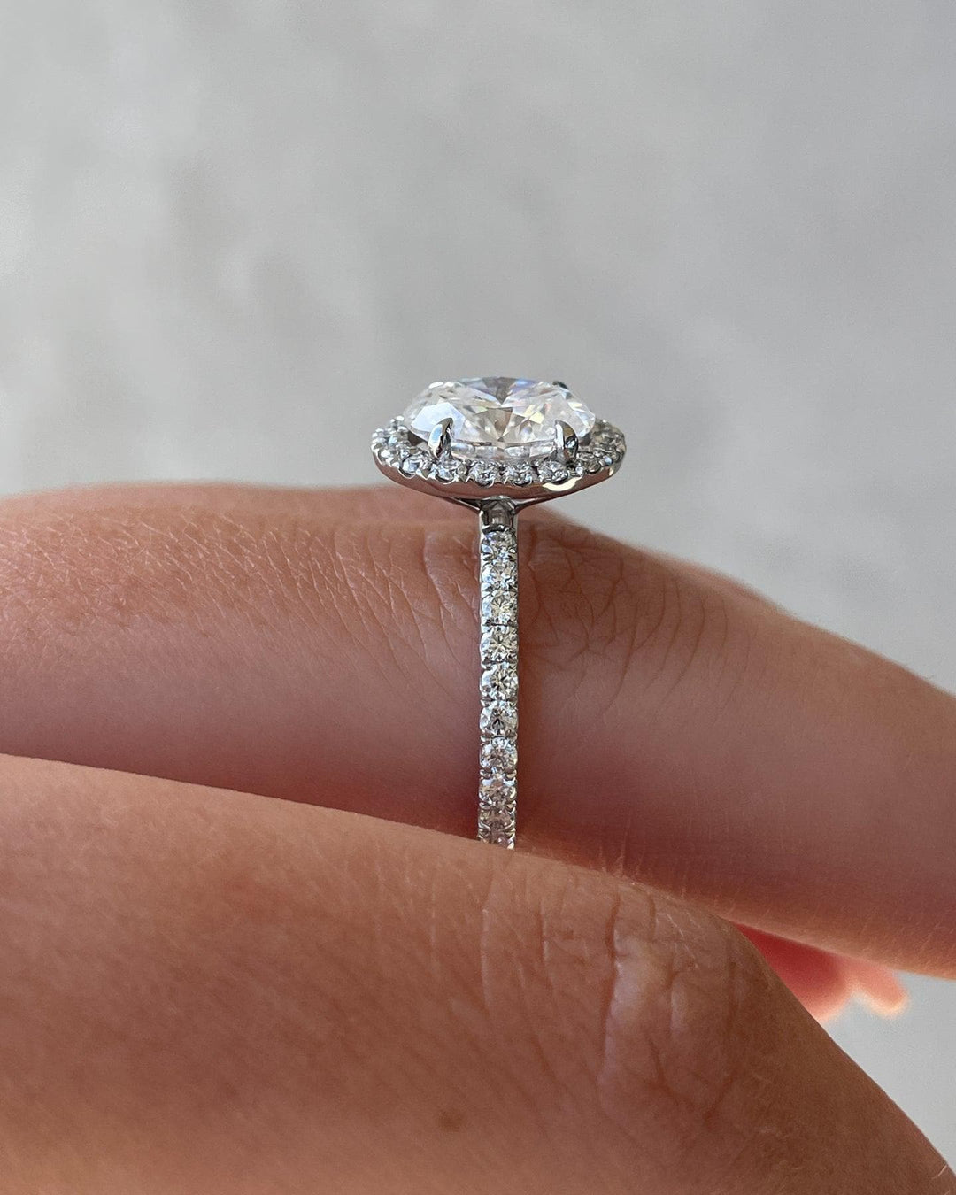 a close up of a person's hand holding a diamond ring