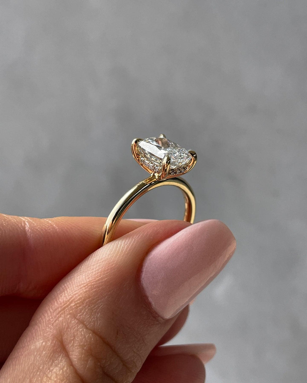 a woman's hand holding a yellow gold ring with a pear shaped diamond