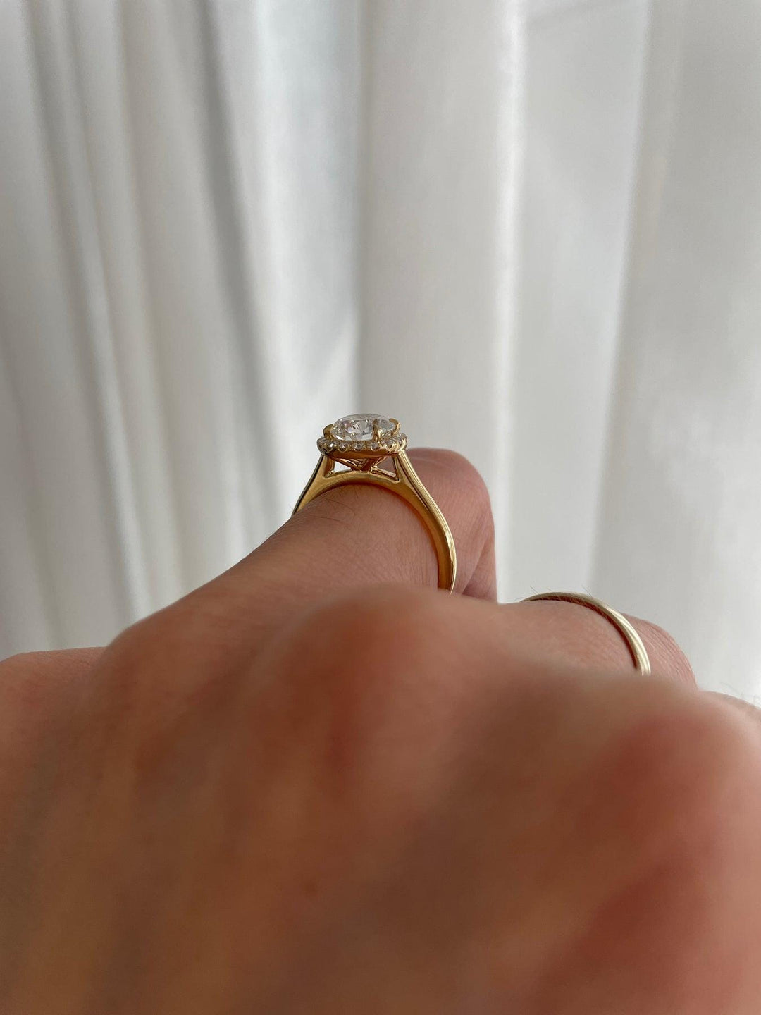 a person's hand holding a ring with a diamond on it