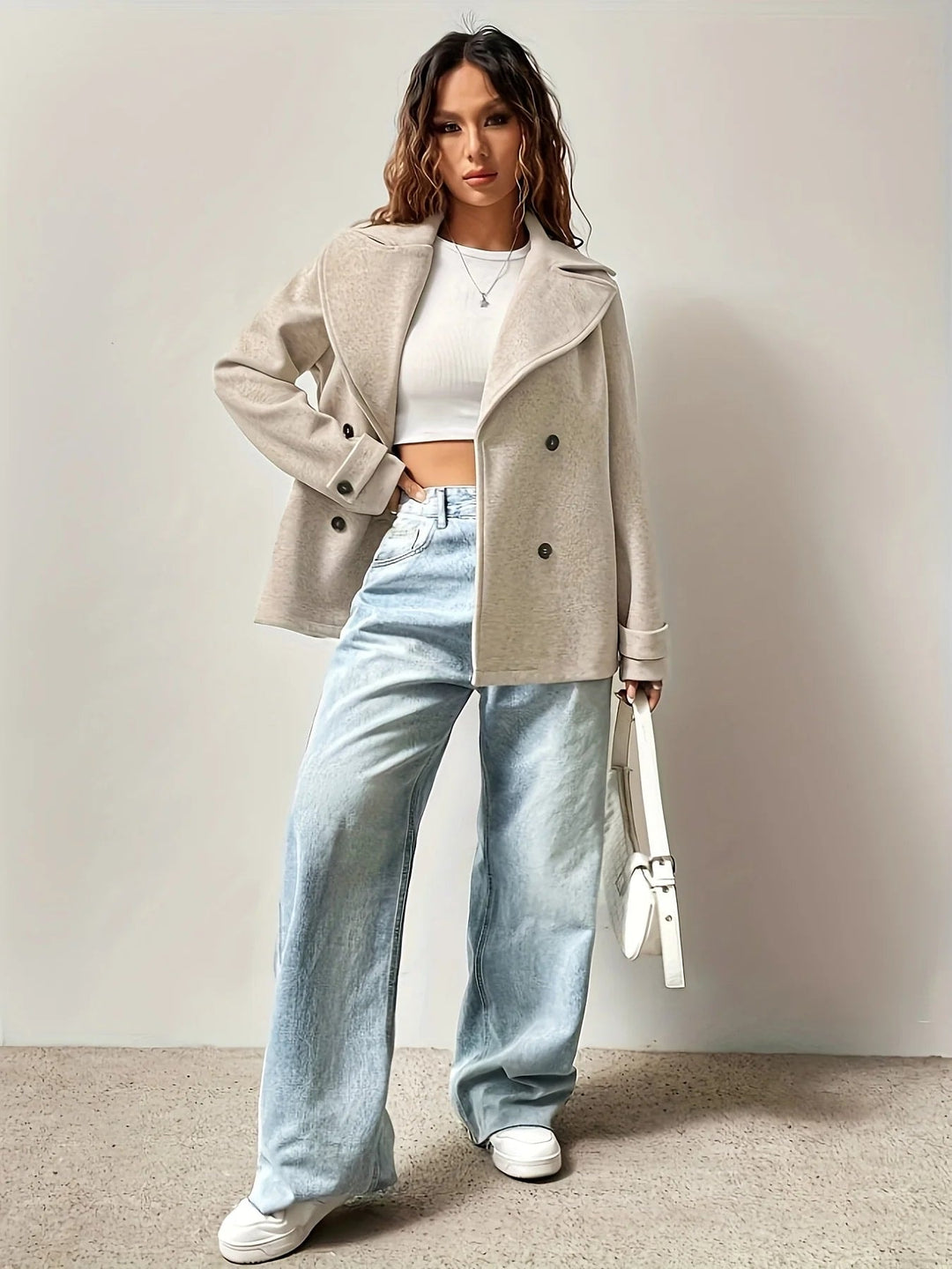 Kvinde i beige frakke med lyse jeans og hvid top