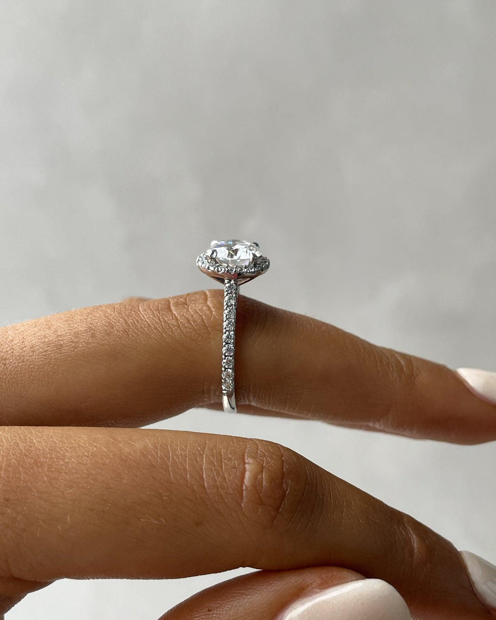 a close up of a person's hand holding a diamond ring