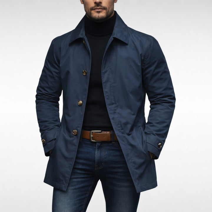 Marineblå frakke til herre med knapper og krave, båret med jeans og brunt bælte