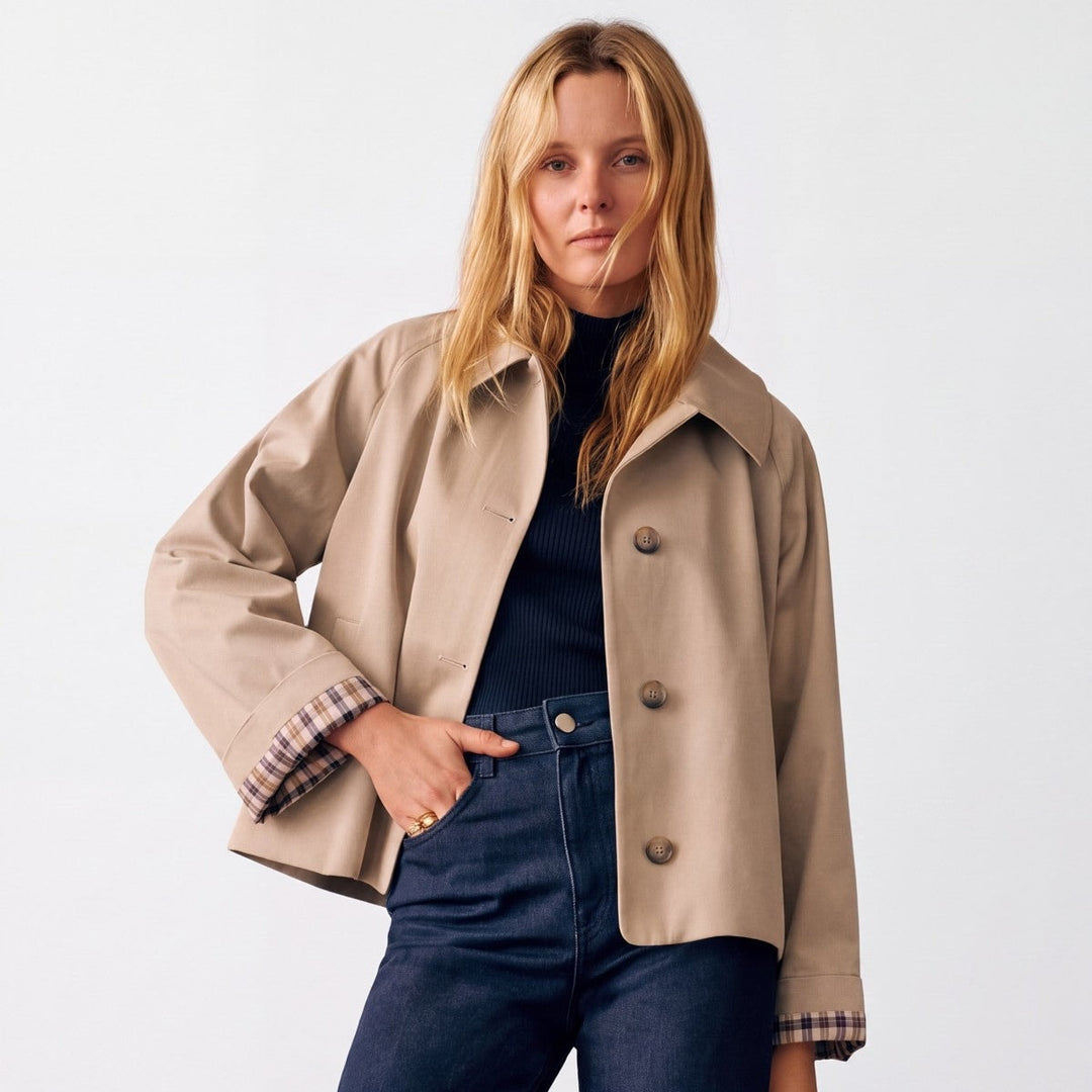 Kort beige trenchcoat til damer med ternet foer i ærmekanten