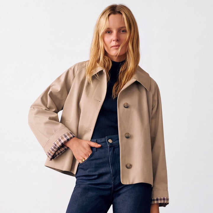 Kort beige trenchcoat til damer med ternet foer i ærmekanten
